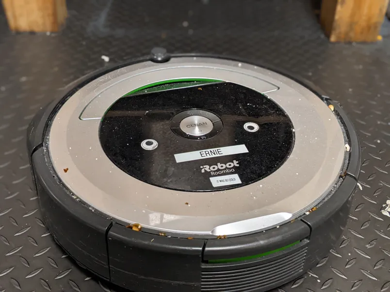 a-close-up-photo-of-a-roomba-on-a-floor-sprinkled-with-popcorn-pieces.webp