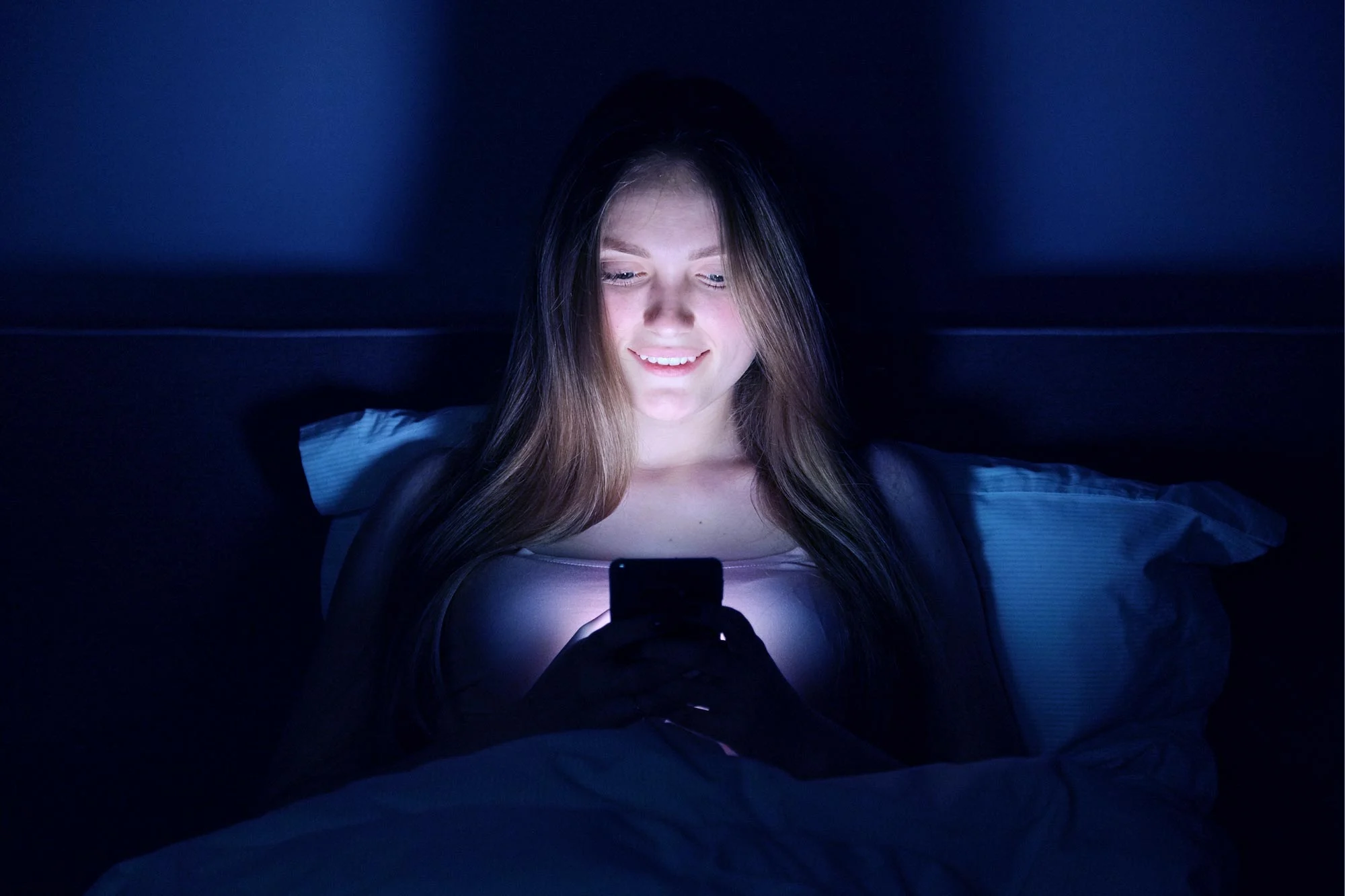 Young-Woman-Smartphone-Bed.webp