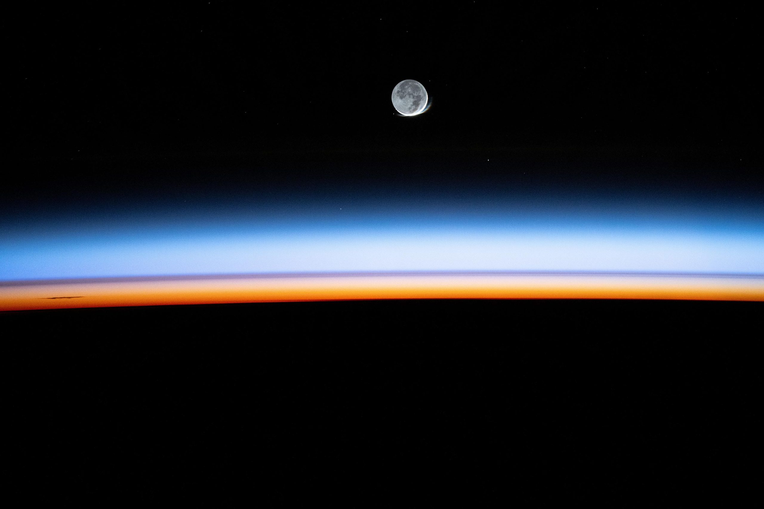 New-Moon-Begins-Setting-Behind-Earths-Colorful-Atmosphere-scaled.jpg