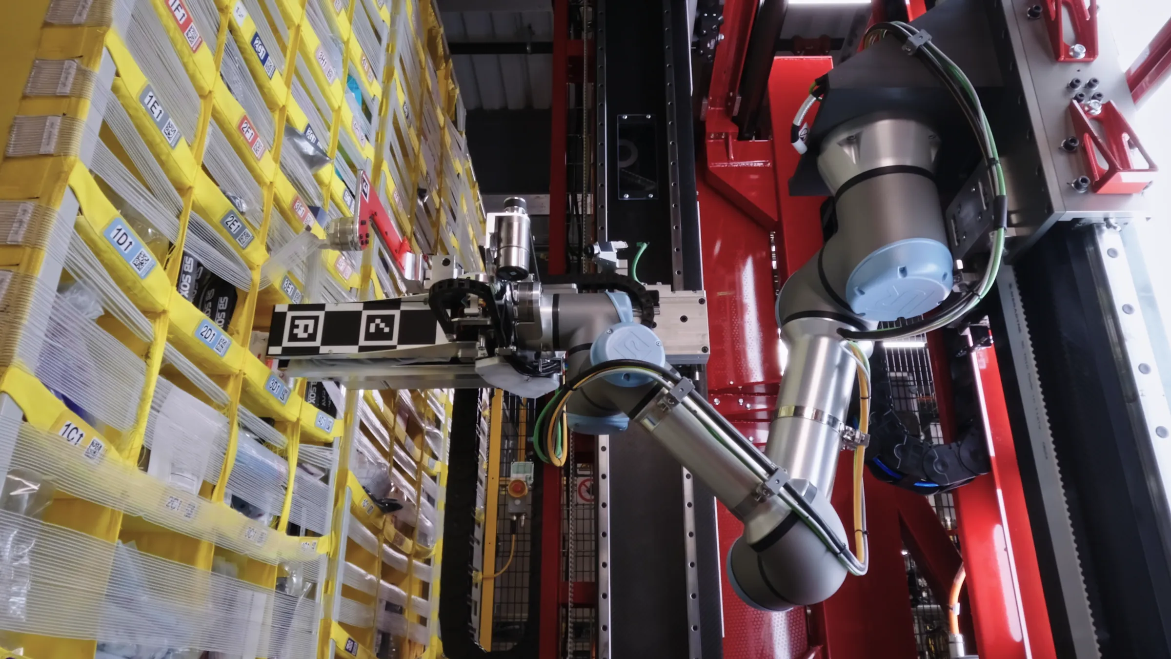 robotic-arm-sorting-yellow-storage-bins-in-a-warehouse-aisle.webp
